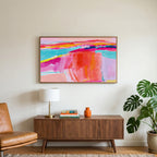 Pink abstract horizon art on a TV above a walnut credenza with a brass lamp and a monstera plant