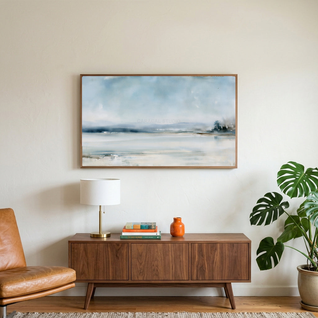 Snowy landscape art on a TV above a walnut credenza with a brass lamp and a monstera plant
