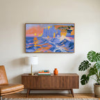 Sunset sea cliffs art on a TV above a walnut credenza with a brass lamp and a monstera plant