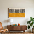 Abstract lines and color block art on a TV above a walnut credenza with a brass lamp and a monstera plant