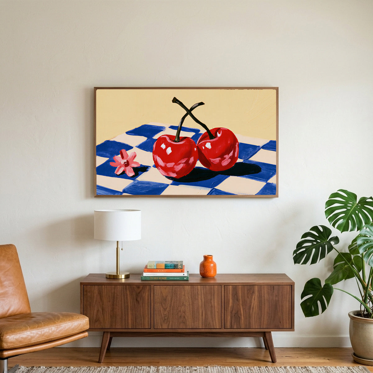 Cherry still life art on a TV above a walnut credenza with a brass lamp and a monstera plant