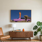 Pink car in the desert art on a TV above a walnut credenza with a brass lamp and a monstera plant