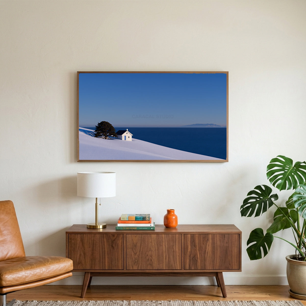 Snowy seaside cottage art on a TV above a walnut credenza with a brass lamp and a monstera plant