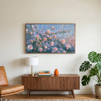 Pink spring flower buds art on a TV above a walnut credenza with a brass lamp and a monstera plant