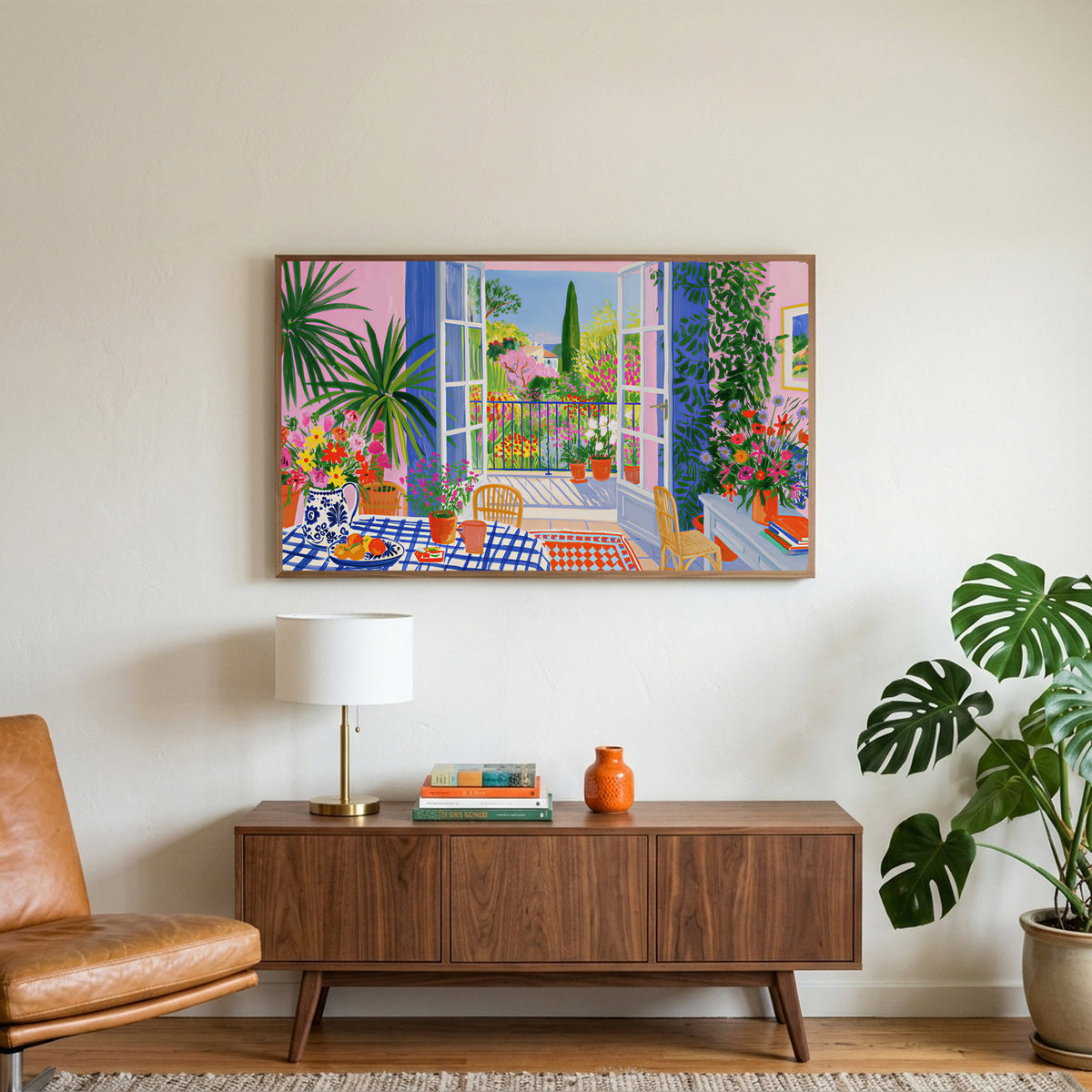 Mediterranean garden view art on a TV above a walnut credenza with a brass lamp and a monstera plant