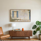 Blue shutter cottage window art on a TV above a walnut credenza with a brass lamp and a monstera plant
