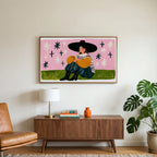 Woman in a big hat art on a TV above a walnut credenza with a brass lamp and a monstera plant
