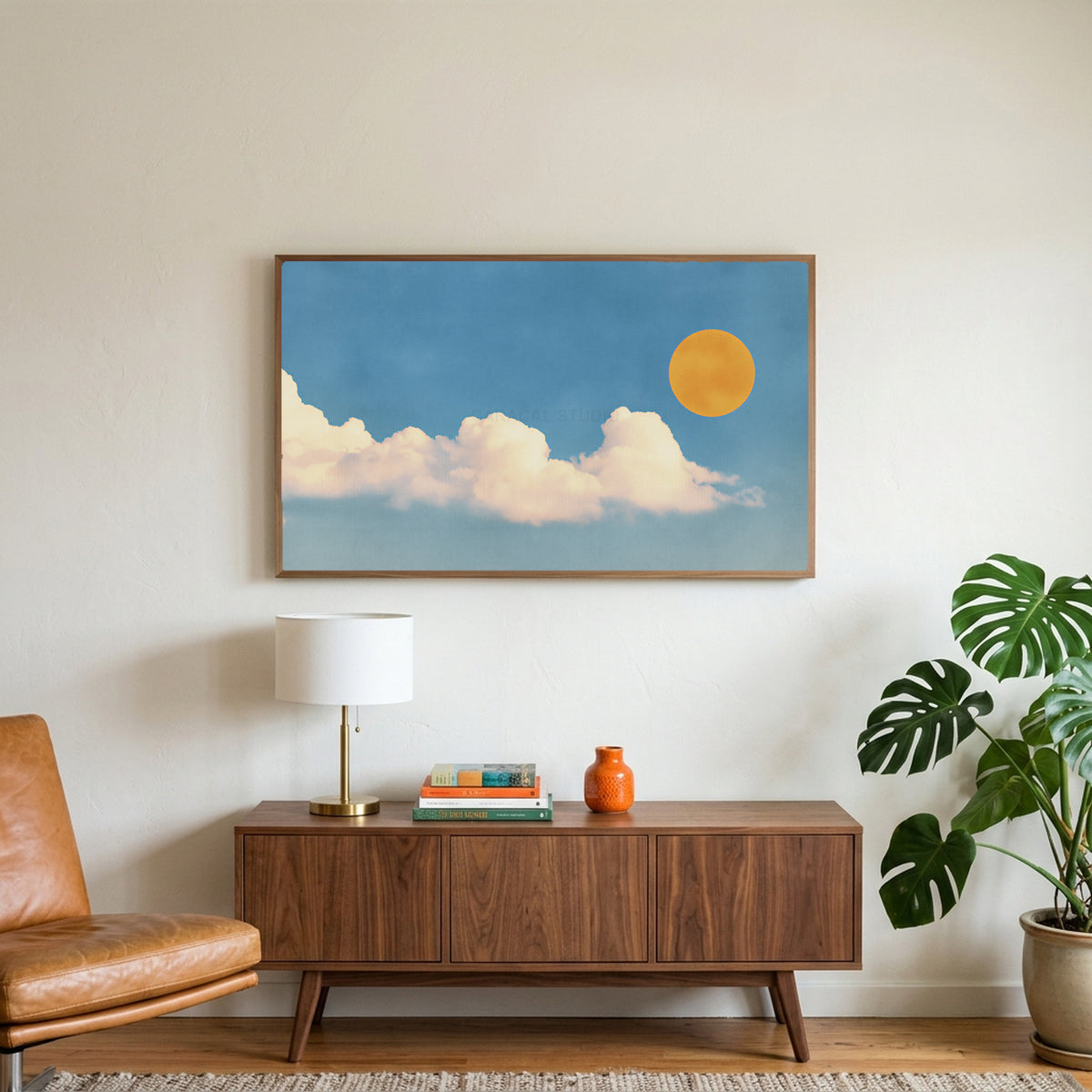 Sun and clouds art on a TV above a walnut credenza with a brass lamp and a monstera plant