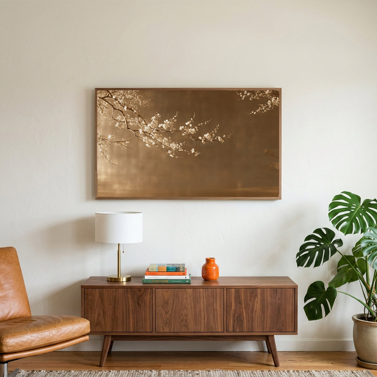 Japanese blossom art on a TV above a walnut credenza with a brass lamp and a monstera plant
