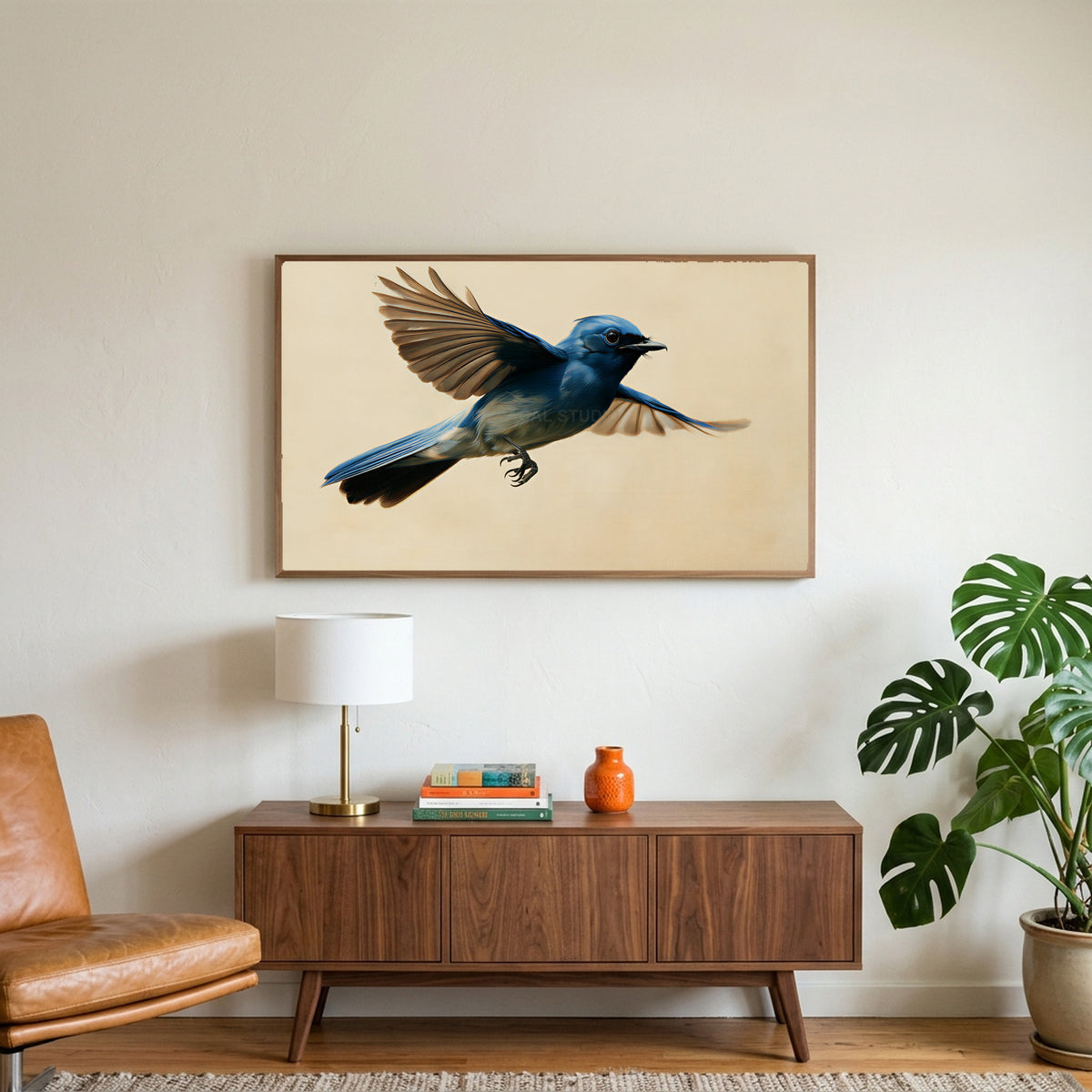 Blue flycatcher art on a TV above a walnut credenza with a brass lamp and a monstera plant