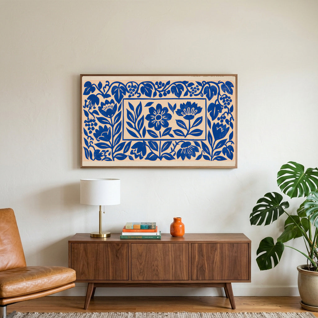 Blue paper cut flowers art on a TV above a walnut credenza with a brass lamp and a monstera plant