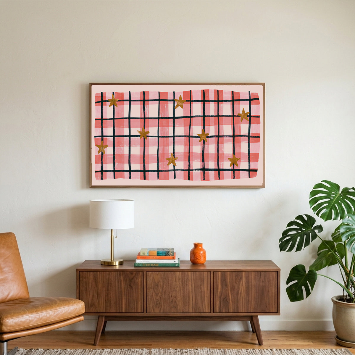 Gingham plaid with stars art on a TV above a walnut credenza with a brass lamp and a monstera plant