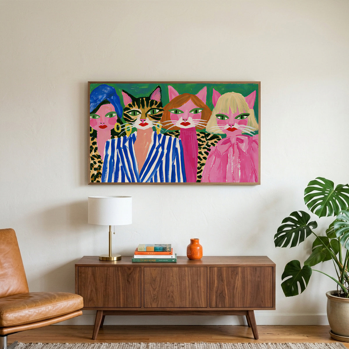 Cat ladies art on a TV above a walnut credenza with a brass lamp and a monstera plant