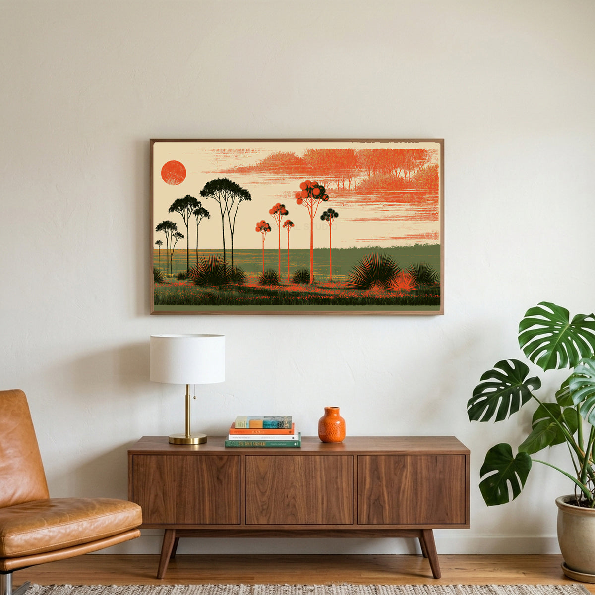 Block print trees art on a TV above a walnut credenza with a brass lamp and a monstera plant