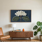 Embroidered hydrangea art on a TV above a walnut credenza with a brass lamp and a monstera plant