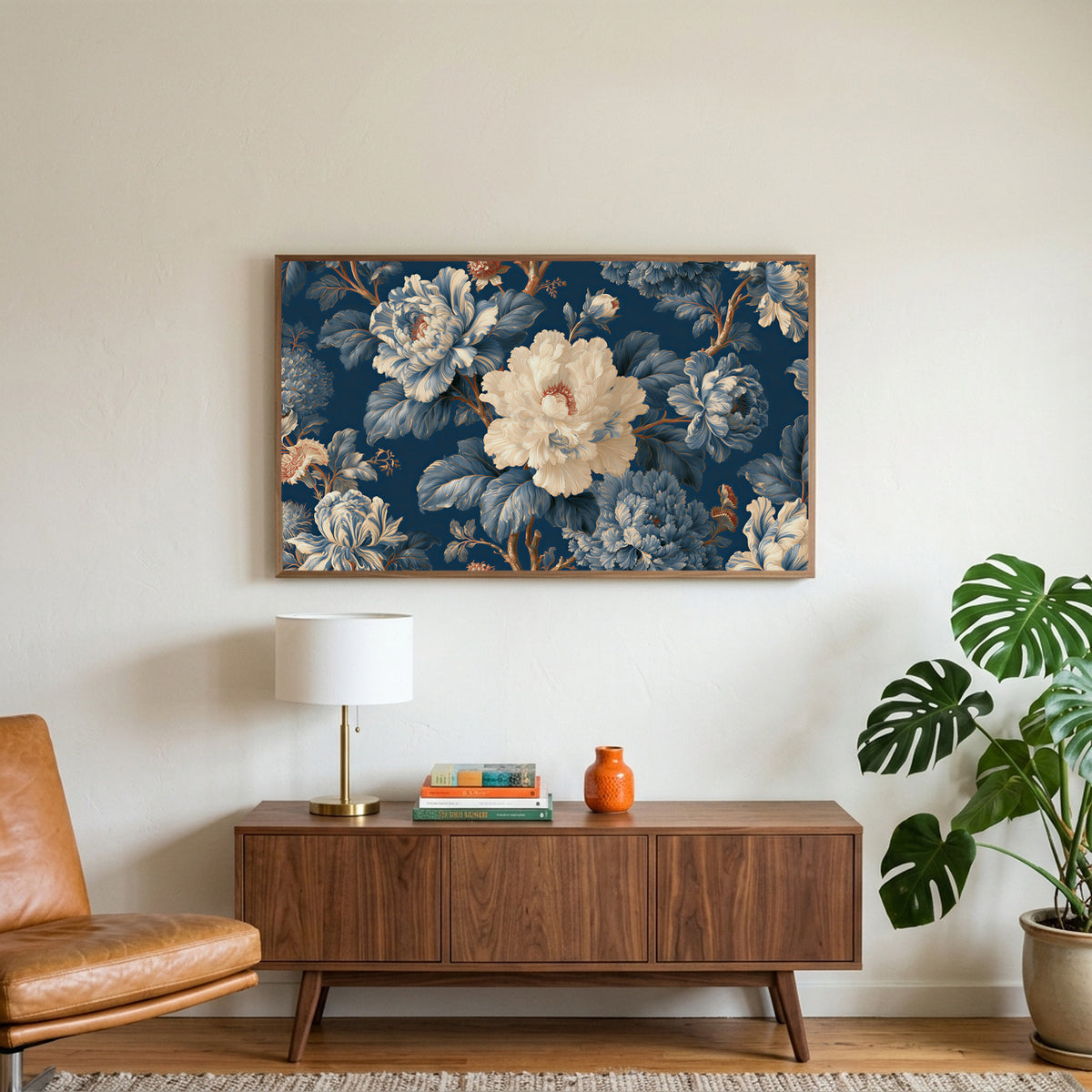 Blue and cream peonies art on a TV above a walnut credenza with a brass lamp and a monstera plant
