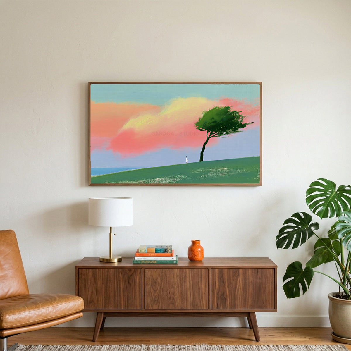 Tree on a hill at sunset art on a TV above a walnut credenza with a brass lamp and a monstera plant
