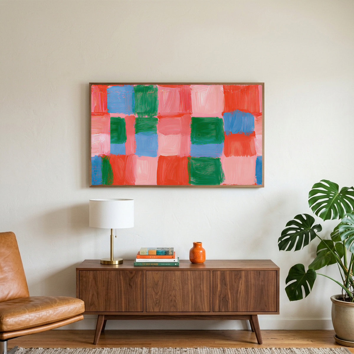 Painted checks art on a TV above a walnut credenza with a brass lamp and a monstera plant