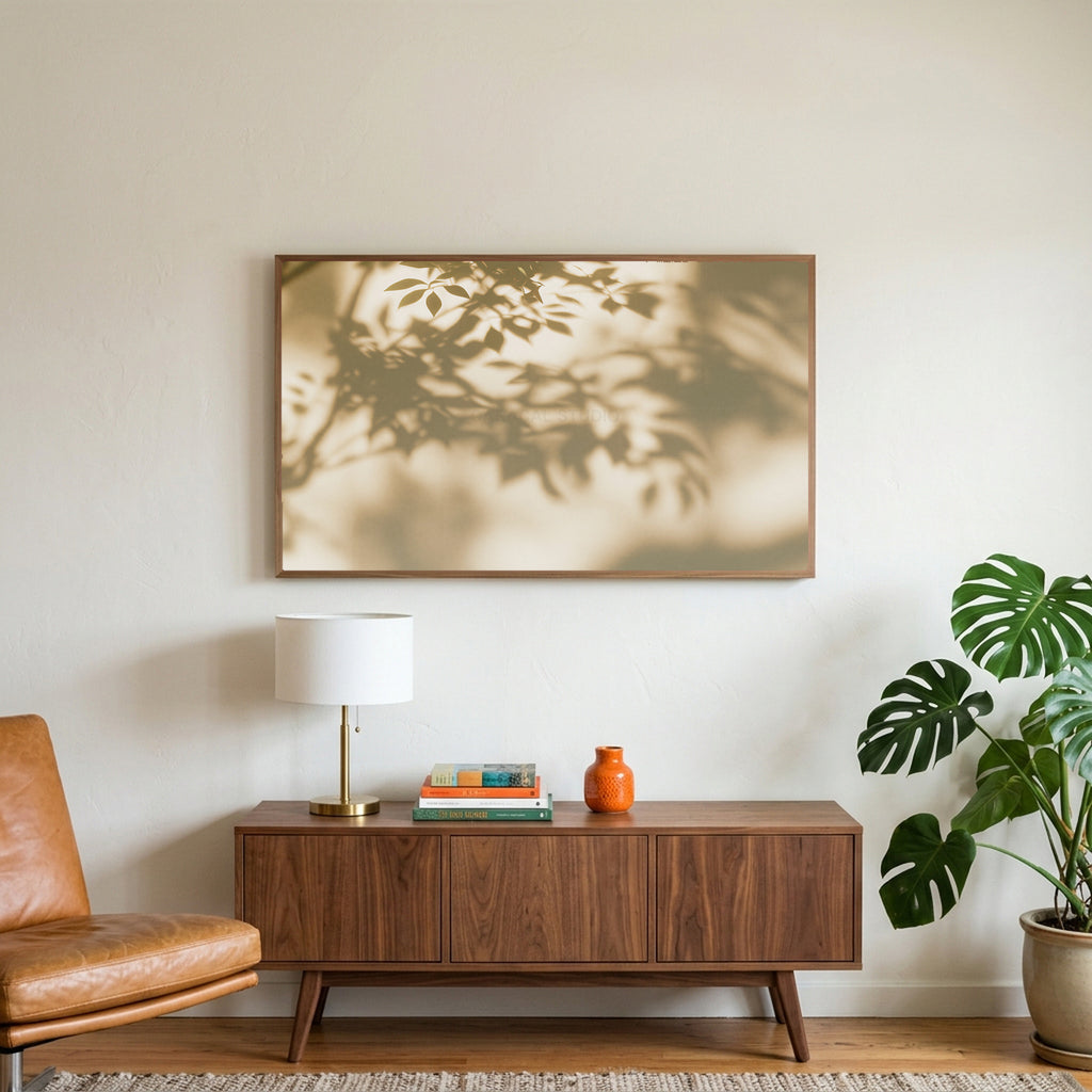 Leaf shadow art on a TV above a walnut credenza with a brass lamp and a monstera plant