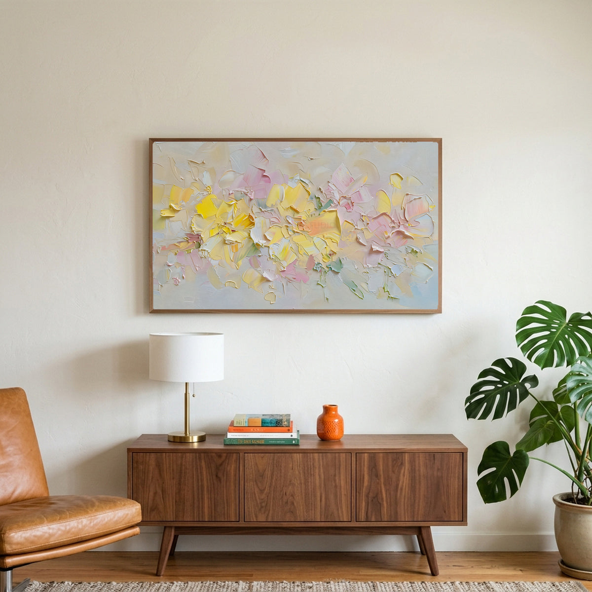 Pastel flower art on a TV above a walnut credenza with a brass lamp and a monstera plant