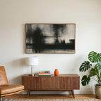 Black and white abstract art on a TV above a walnut credenza with a brass lamp and a monstera plant