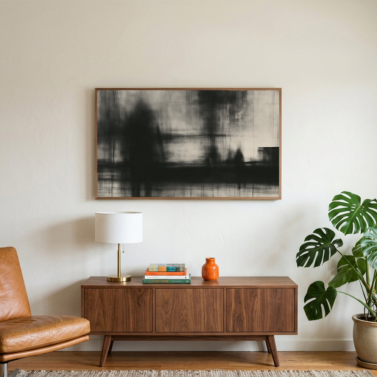 Black and white abstract art on a TV above a walnut credenza with a brass lamp and a monstera plant