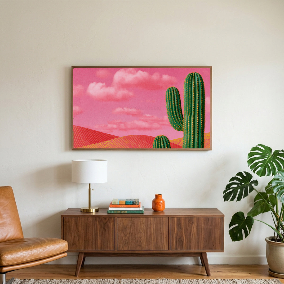 Saguaro cactus art on a TV above a walnut credenza with a brass lamp and a monstera plant