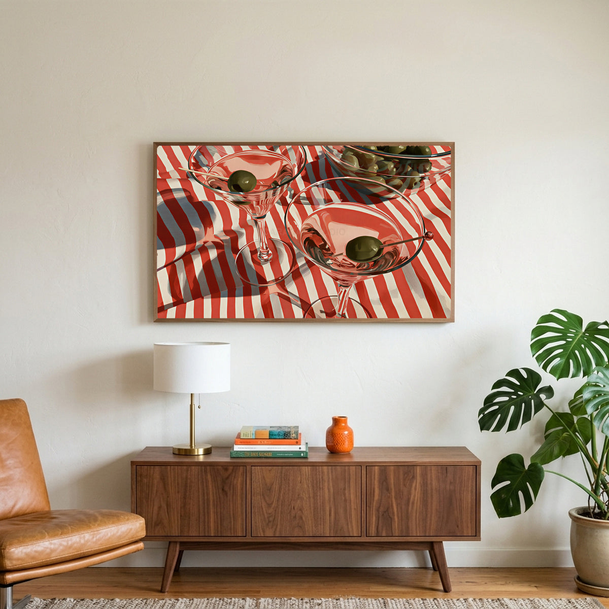 Martini cocktails art on a TV above a walnut credenza with a brass lamp and a monstera plant