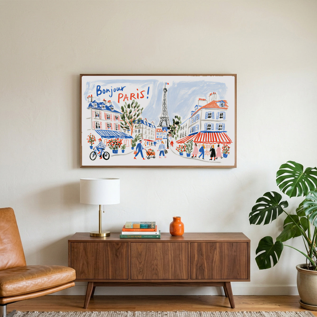 Bonjour Paris art on a TV above a walnut credenza with a brass lamp and a monstera plant