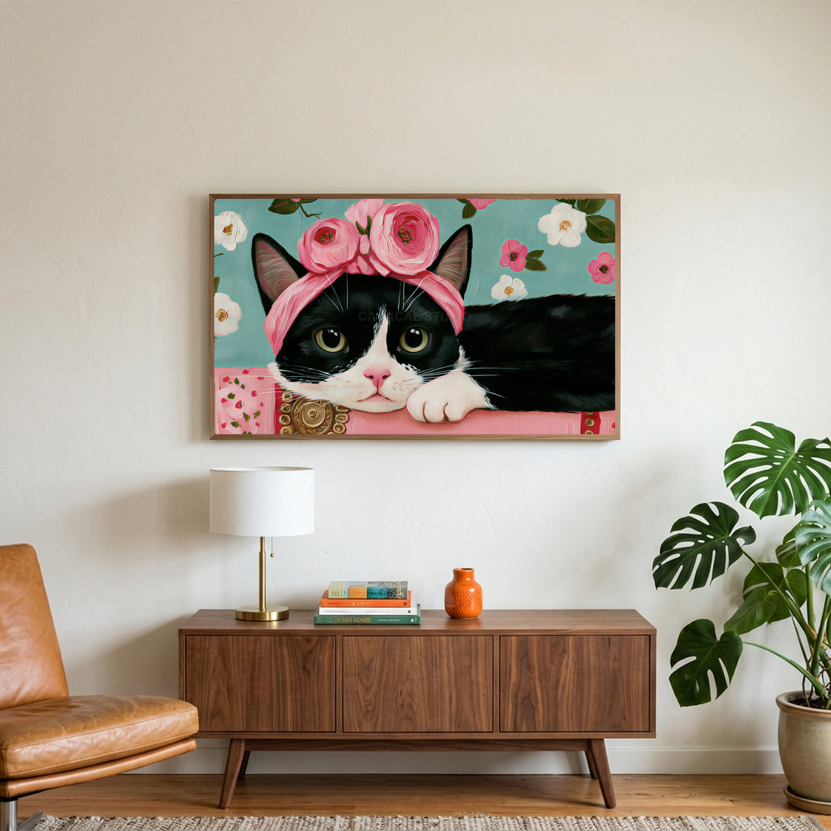 Cat with a flower crown art on a TV above a walnut credenza with a brass lamp and a monstera plant