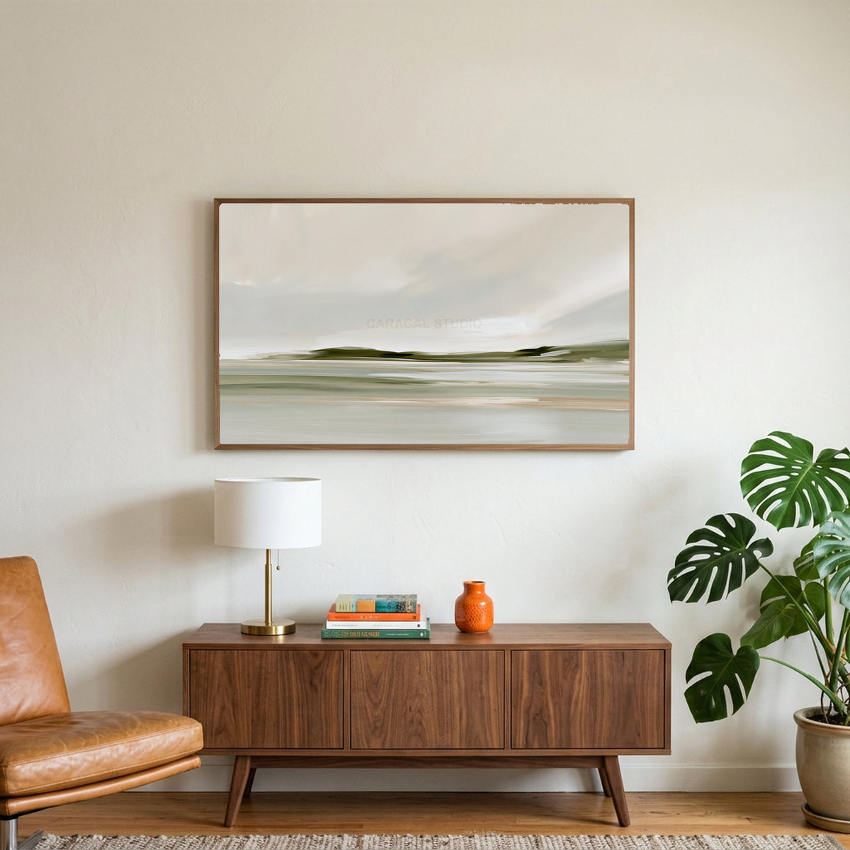 Misty sage shoreline art on a TV above a walnut credenza with a brass lamp and a monstera plant