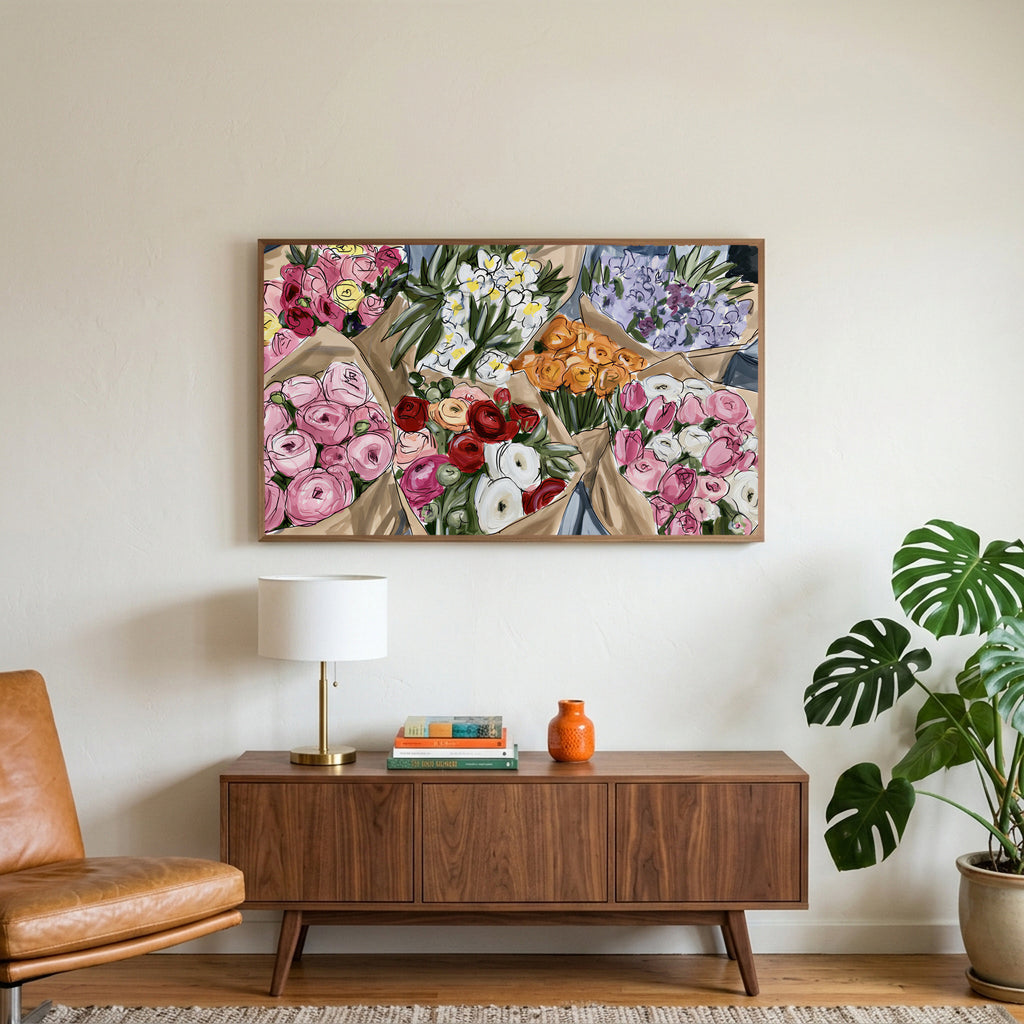 Flower bouquets art on a TV above a walnut credenza with a brass lamp and a monstera plant