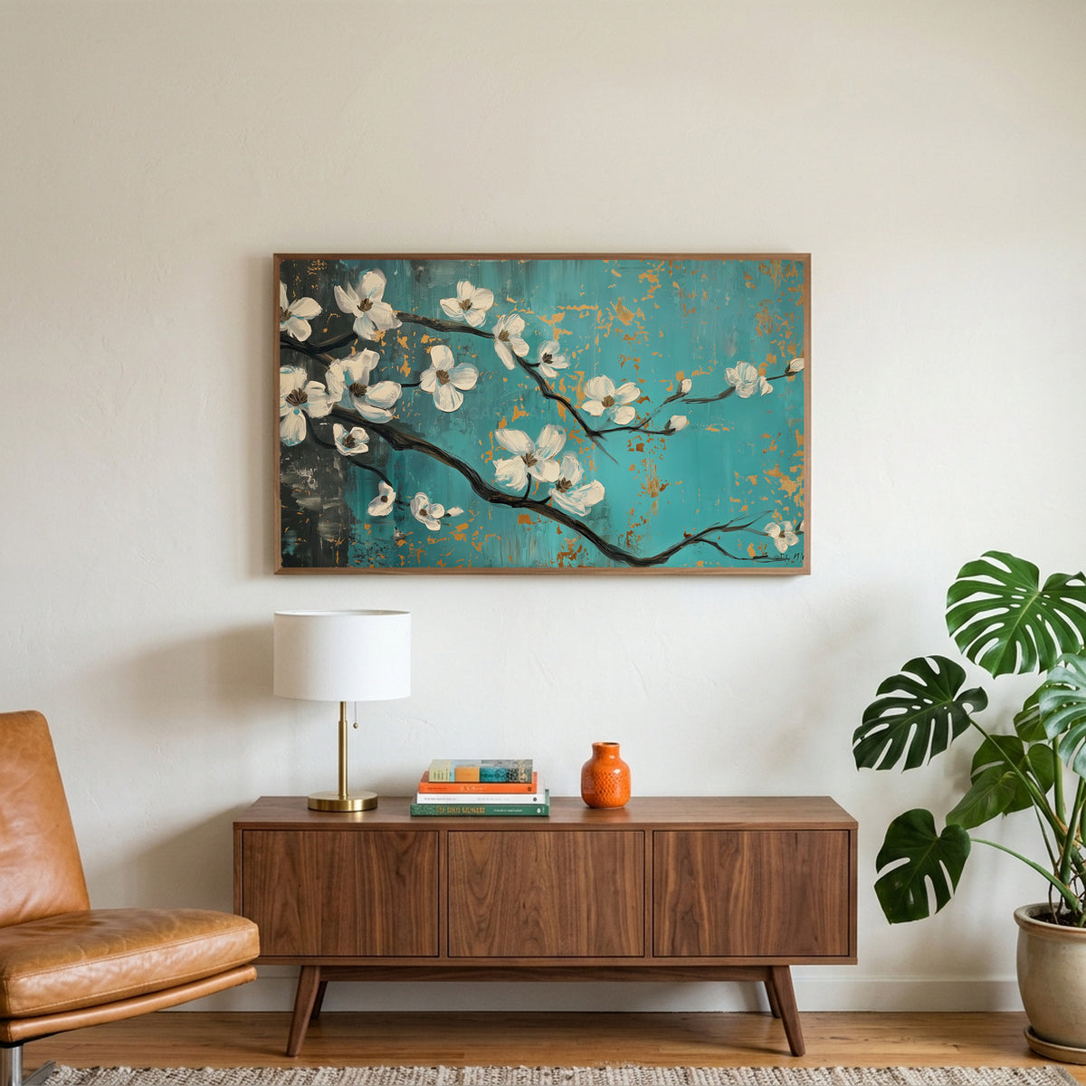 Dogwood blossom art on a TV above a walnut credenza with a brass lamp and a monstera plant