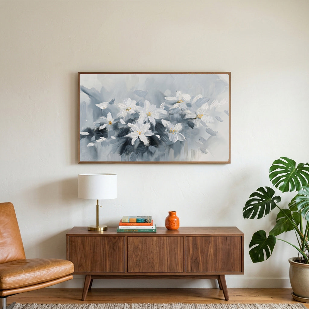 White flower art on a TV above a walnut credenza with a brass lamp and a monstera plant
