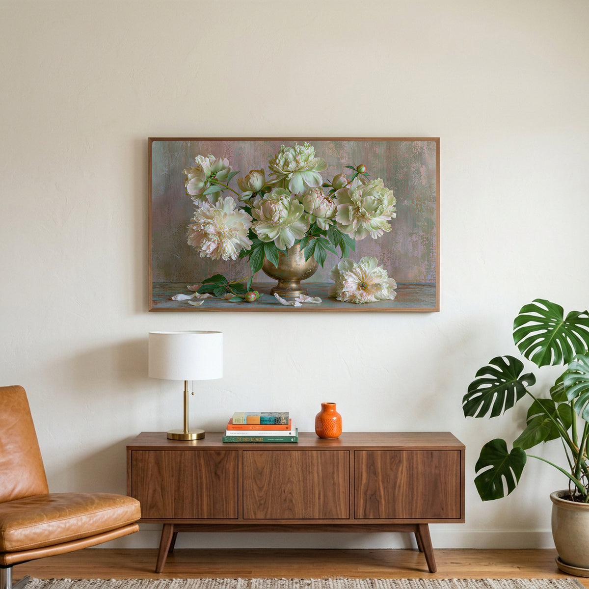 Peonies in a brass urn art on a TV above a walnut credenza with a brass lamp and a monstera plant