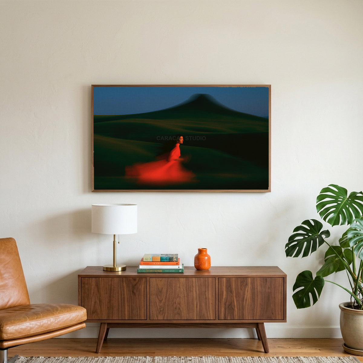Woman running over green hills art on a TV above a walnut credenza with a brass lamp and a monstera plant