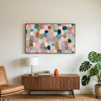 Pastel pebble mosaic art on a TV above a walnut credenza with a brass lamp and a monstera plant
