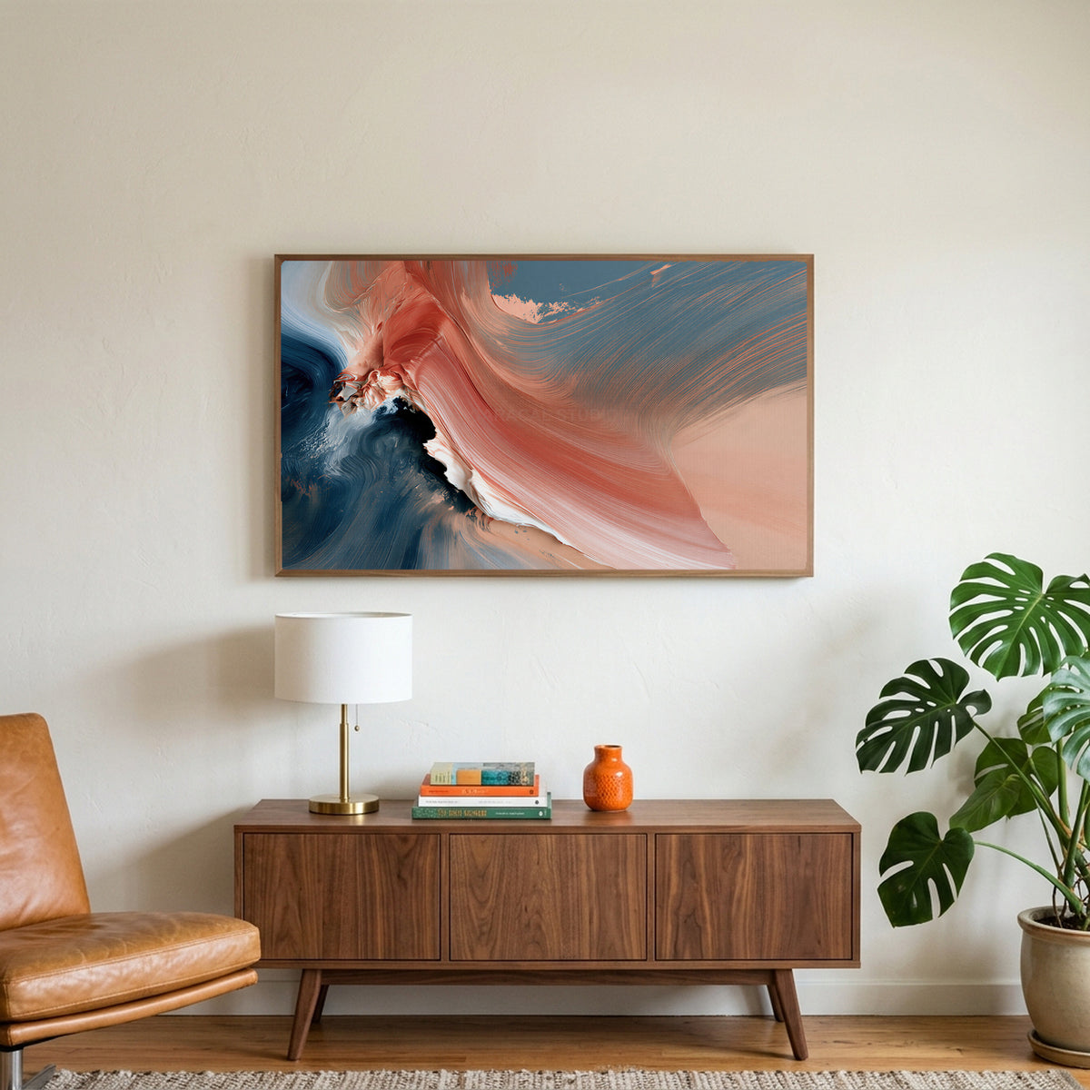 Coral and navy abstract art on a TV above a walnut credenza with a brass lamp and a monstera plant
