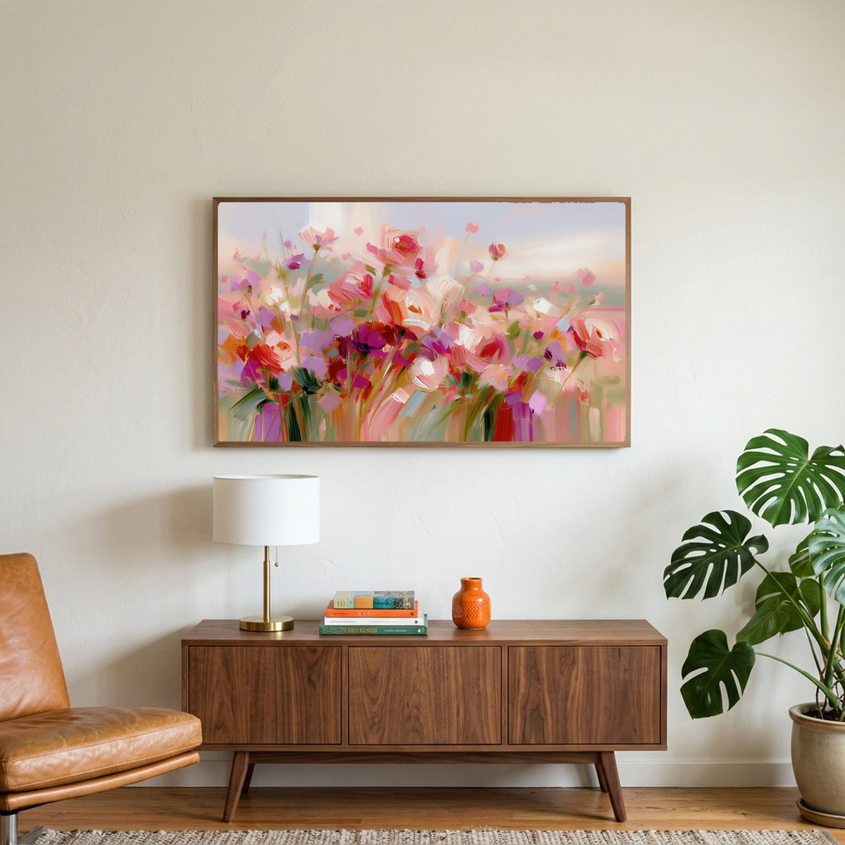 Pink wildflower meadow art on a TV above a walnut credenza with a brass lamp and a monstera plant