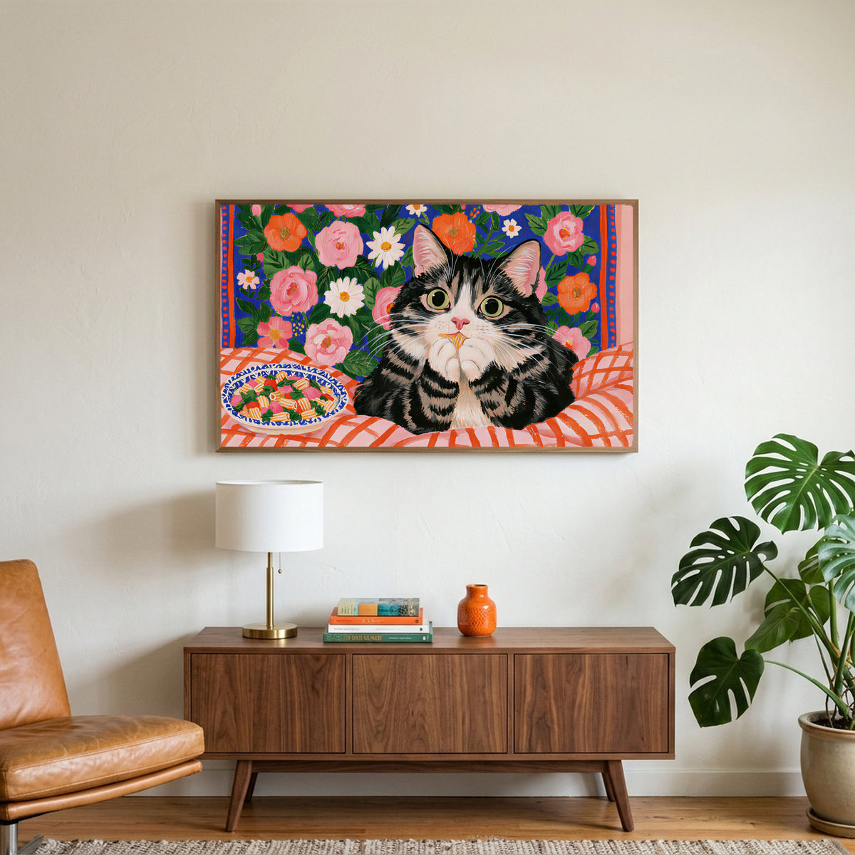 Pasta cat art on a TV above a walnut credenza with a brass lamp and a monstera plant