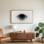 Black and white eye art on a TV above a walnut credenza with a brass lamp and a monstera plant