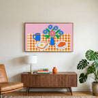 Breakfast table with flowers art on a TV above a walnut credenza with a brass lamp and a monstera plant