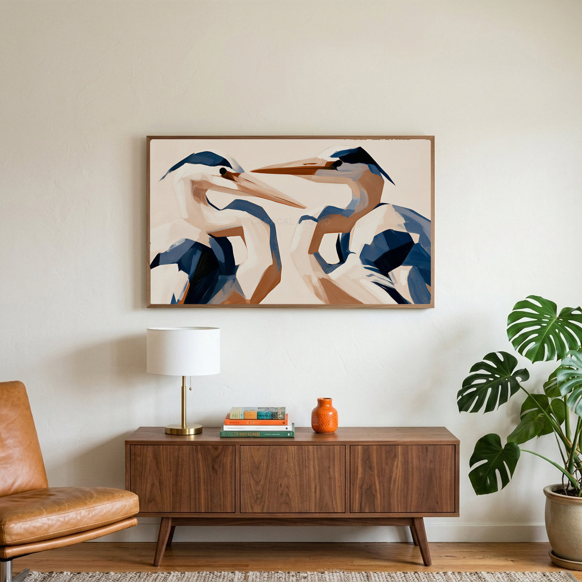 Blue heron art on a TV above a walnut credenza with a brass lamp and a monstera plant