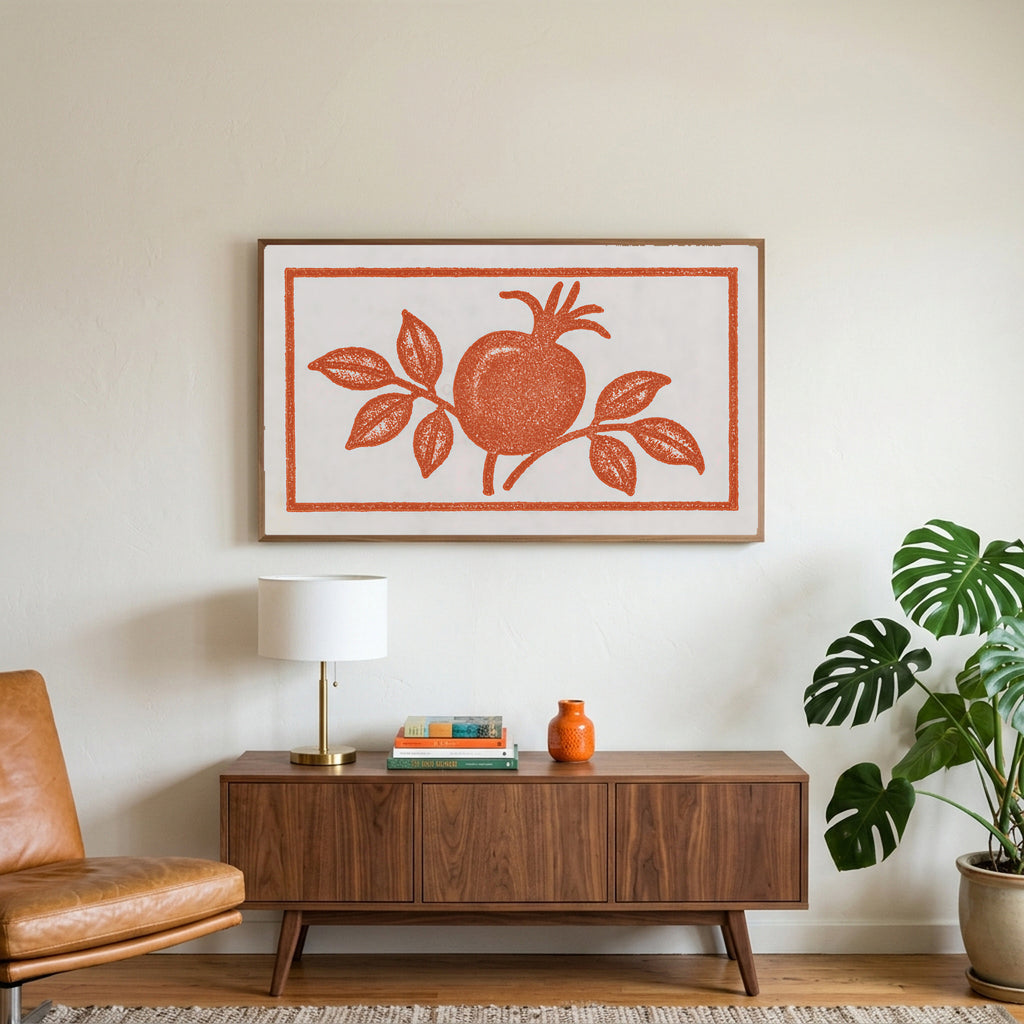 Pomegranate linocut art on a TV above a walnut credenza with a brass lamp and a monstera plant