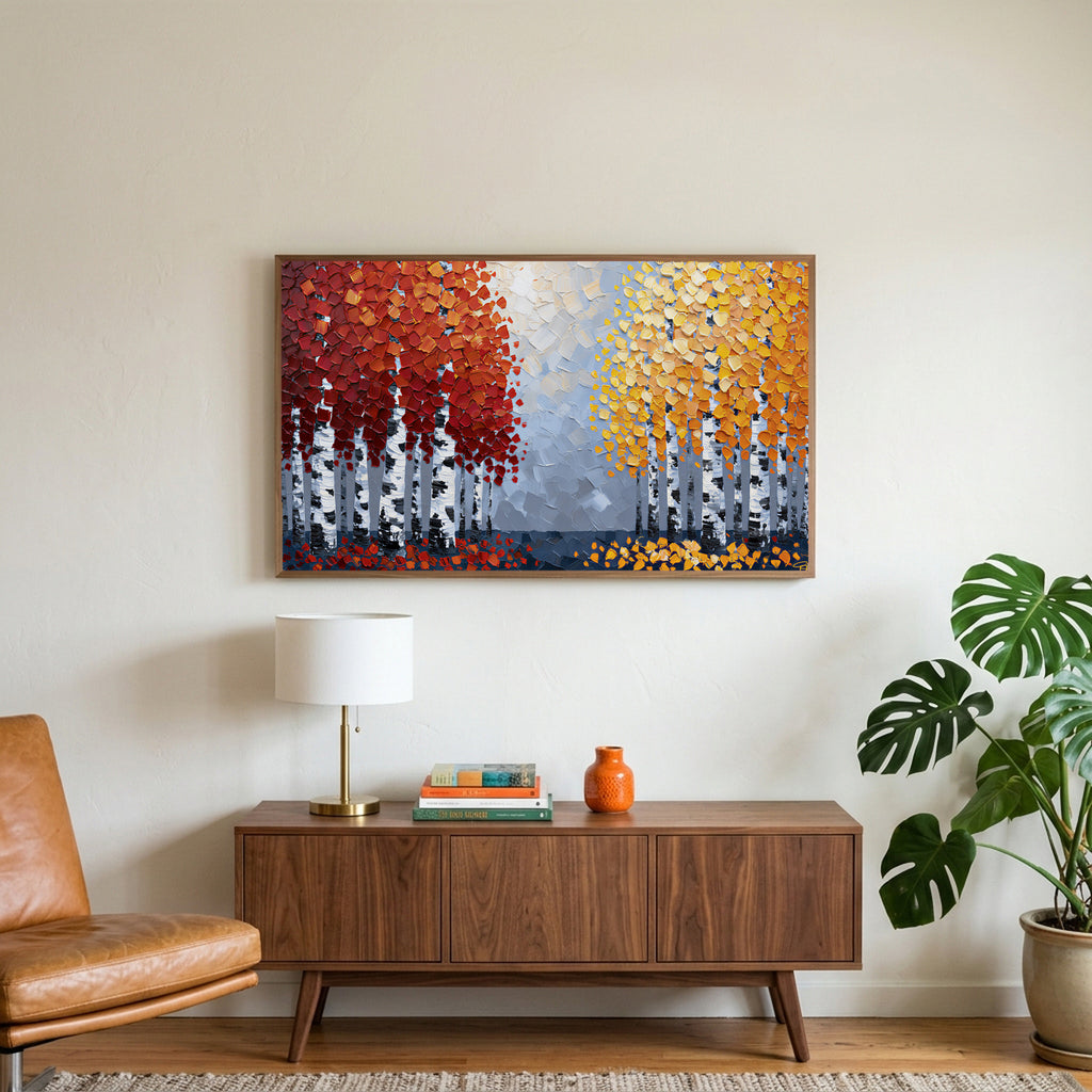 Autumn birch trees art on a TV above a walnut credenza with a brass lamp and a monstera plant