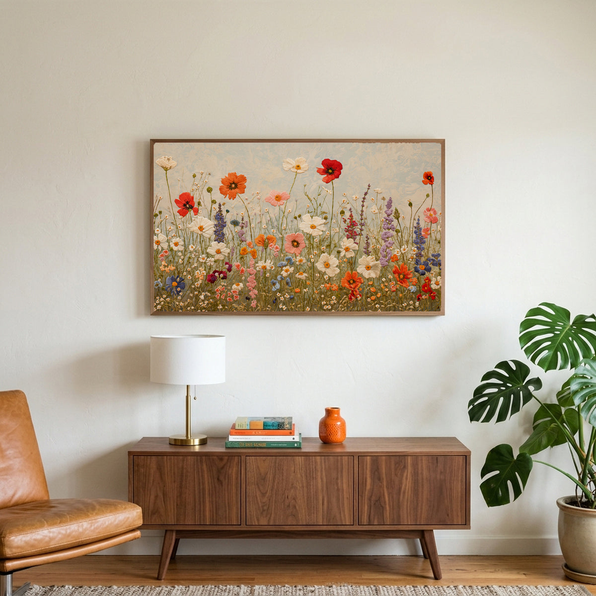 Wildflower meadow art on a TV above a walnut credenza with a brass lamp and a monstera plant