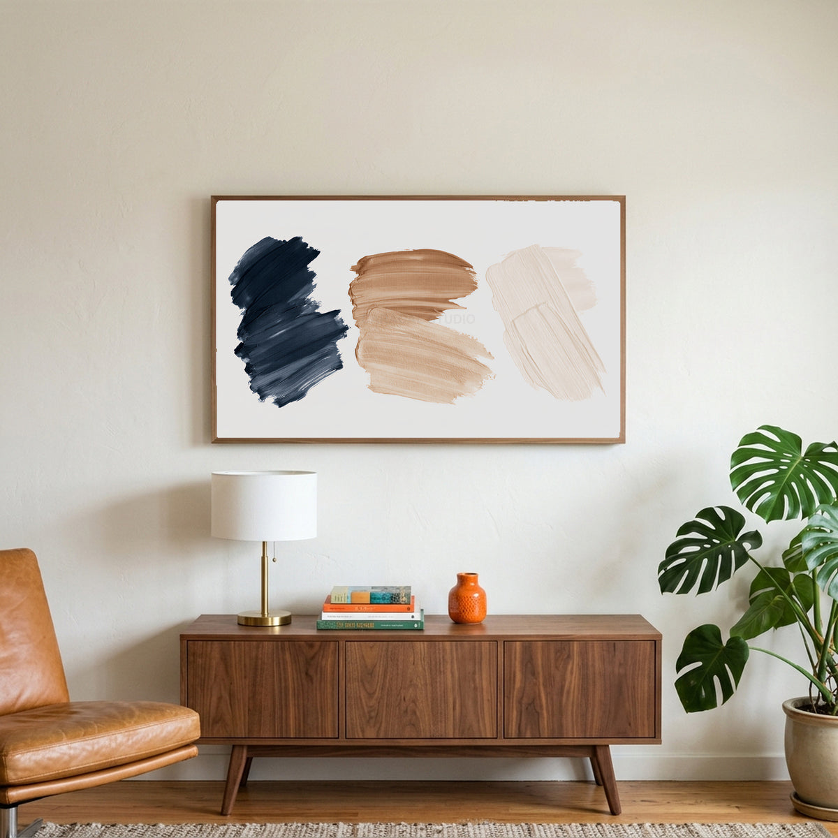 Paint stroke art on a TV above a walnut credenza with a brass lamp and a monstera plant
