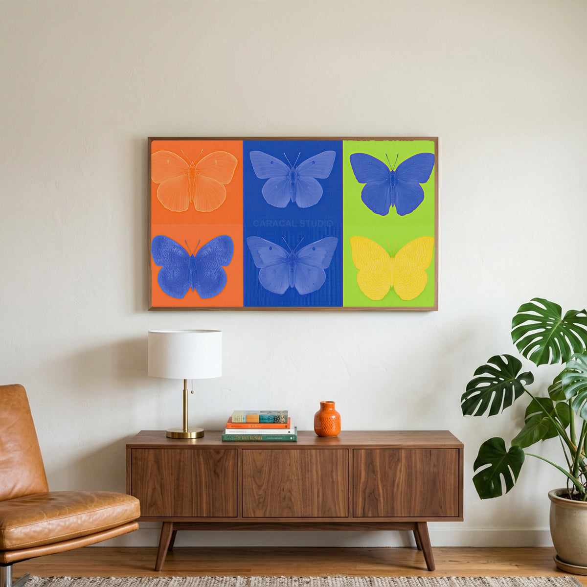 Pop art butterfly art on a TV above a walnut credenza with a brass lamp and a monstera plant