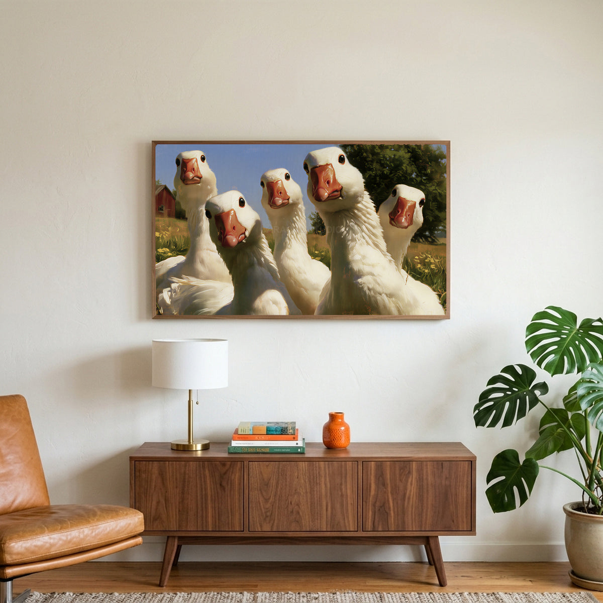 Curious white geese art on a TV above a walnut credenza with a brass lamp and a monstera plant
