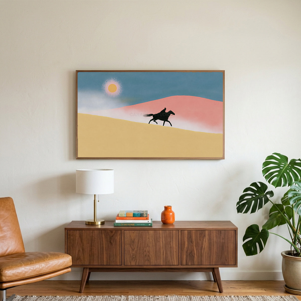 Rider in the desert art on a TV above a walnut credenza with a brass lamp and a monstera plant